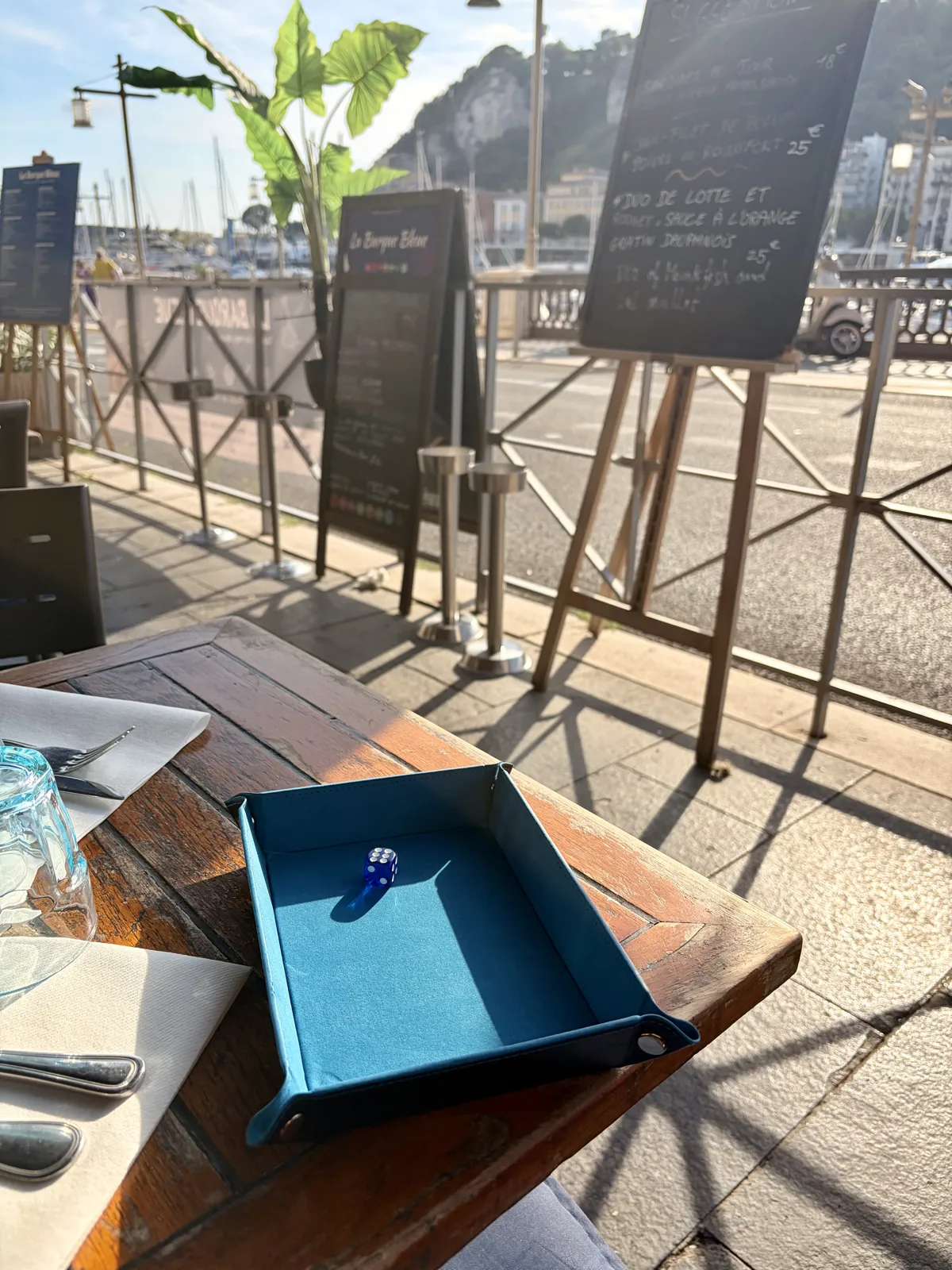 The dice of La Barque Bleue on its tray, facing the Port of Nice